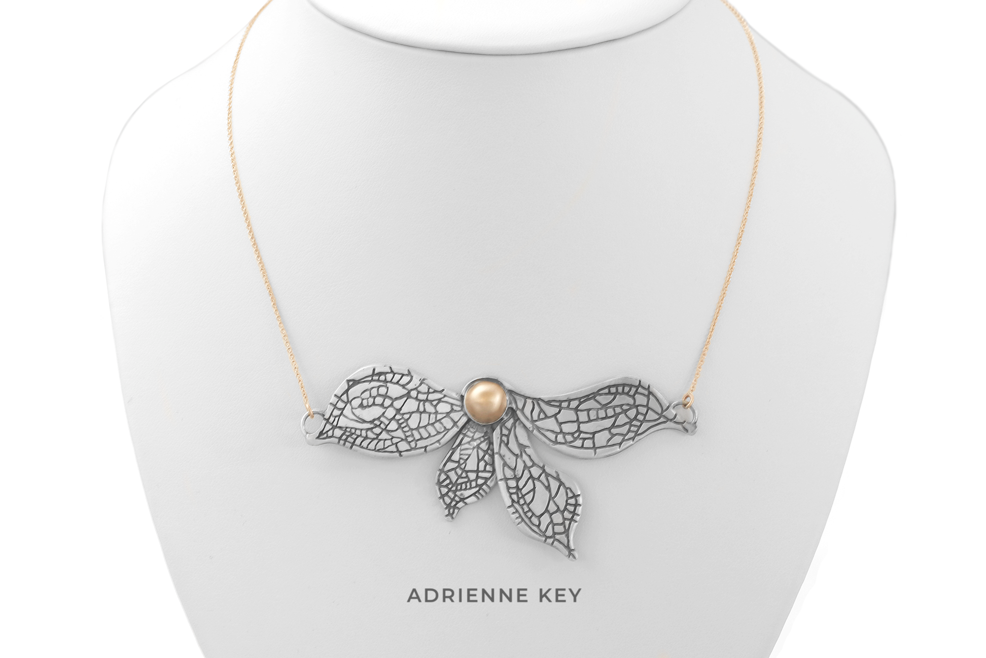 Sterling silver half flower necklace with blackened veins and a 14k yellow gold center sitting on a 14k yellow gold chain