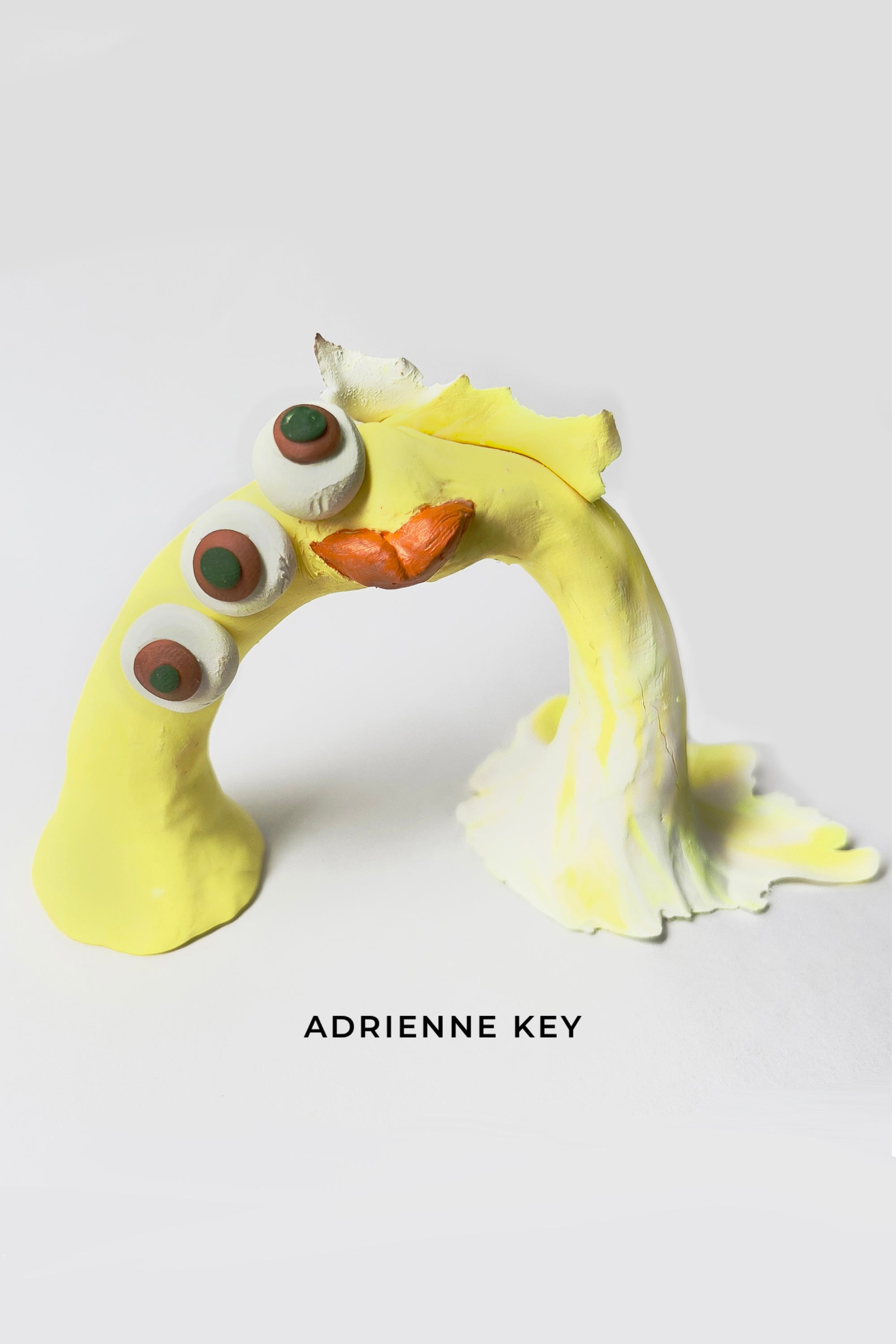 Bright yellow hand sculpted polymer clay, rainbow shaped monster with colorful details