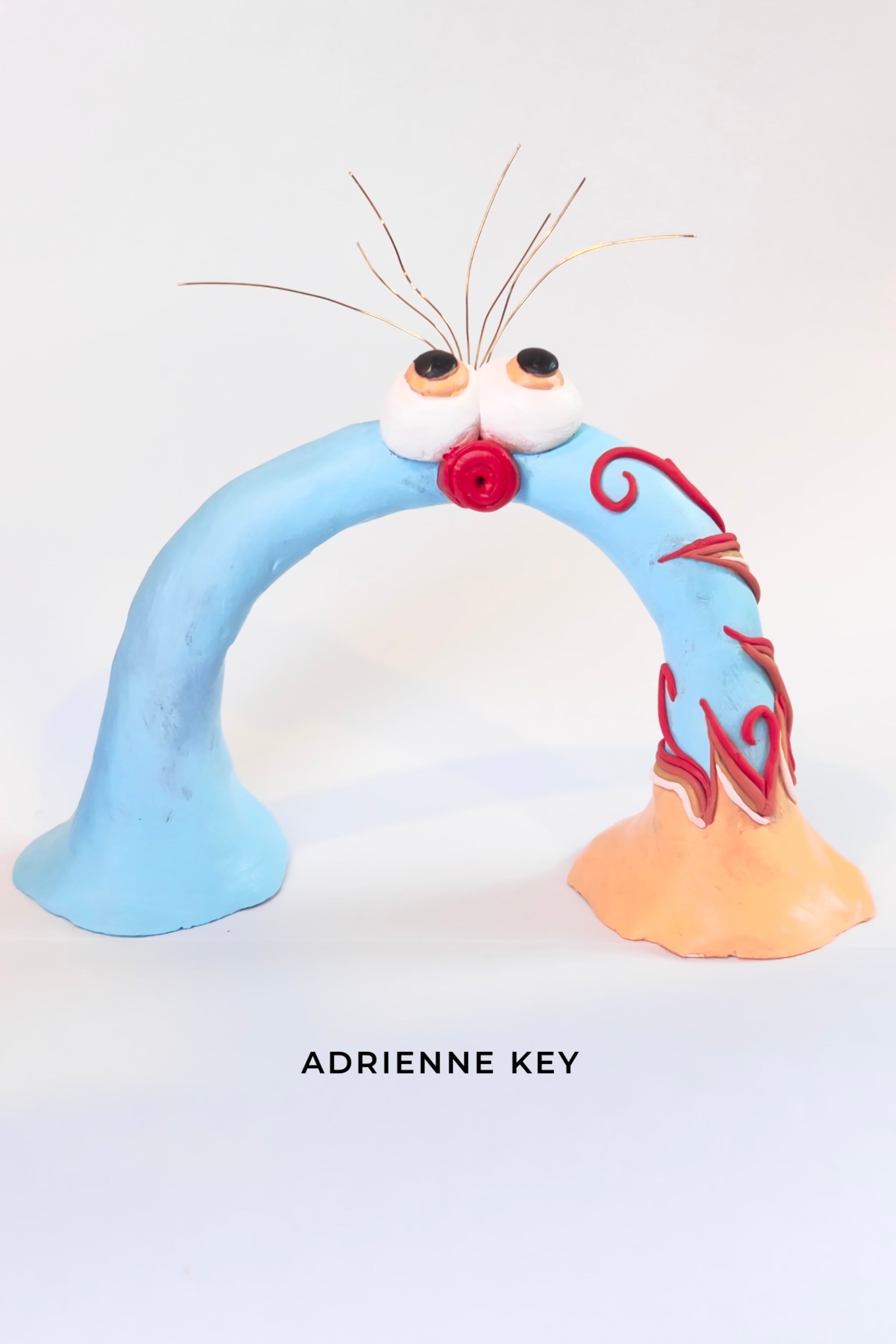 Blue hand sculpted polymer clay, rainbow shaped monster with colorful swirl details