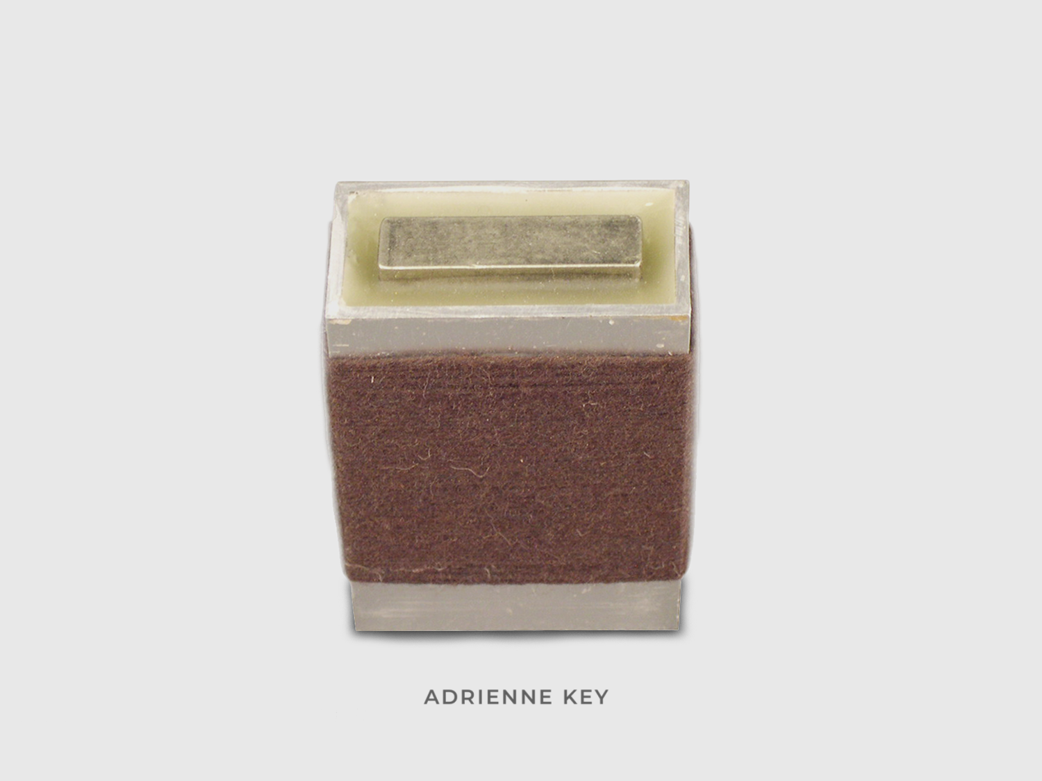 Sculpture of a found aluminum box wrapped in brown cotton string and filled with beeswax with a sunken steel bar