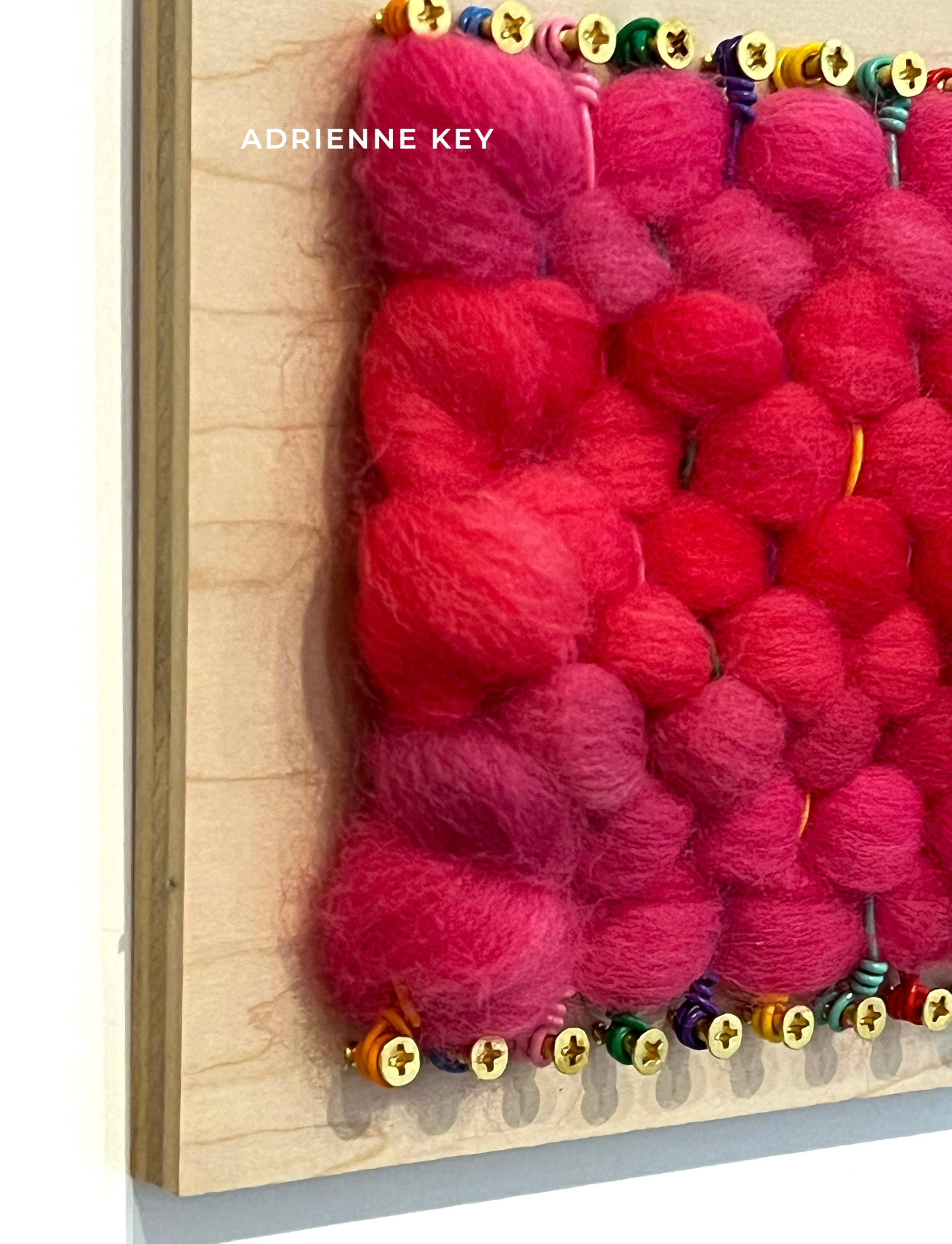 Detail of an original bright colorful wall art piece on 6x6 inch wood base with pink woven wool